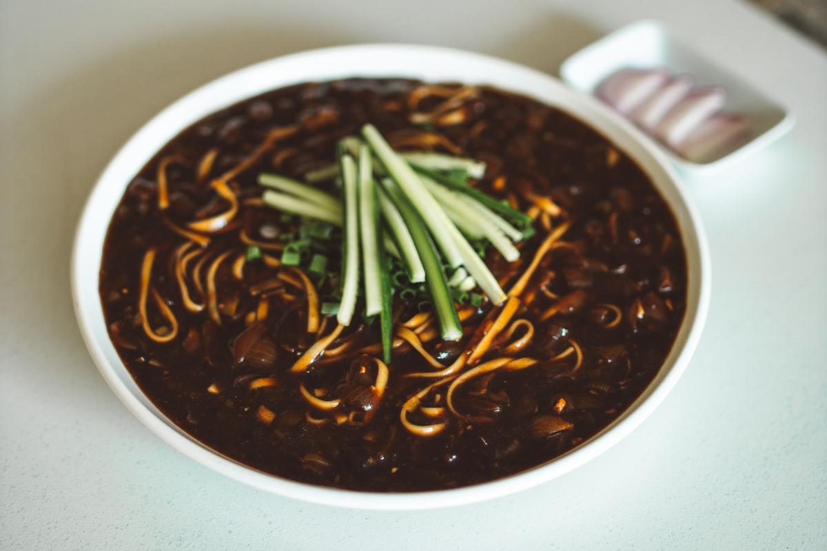 A bowl of jajangmyeon, black bean noodles with fresh cucumber on top, a Korean-Chinese dish