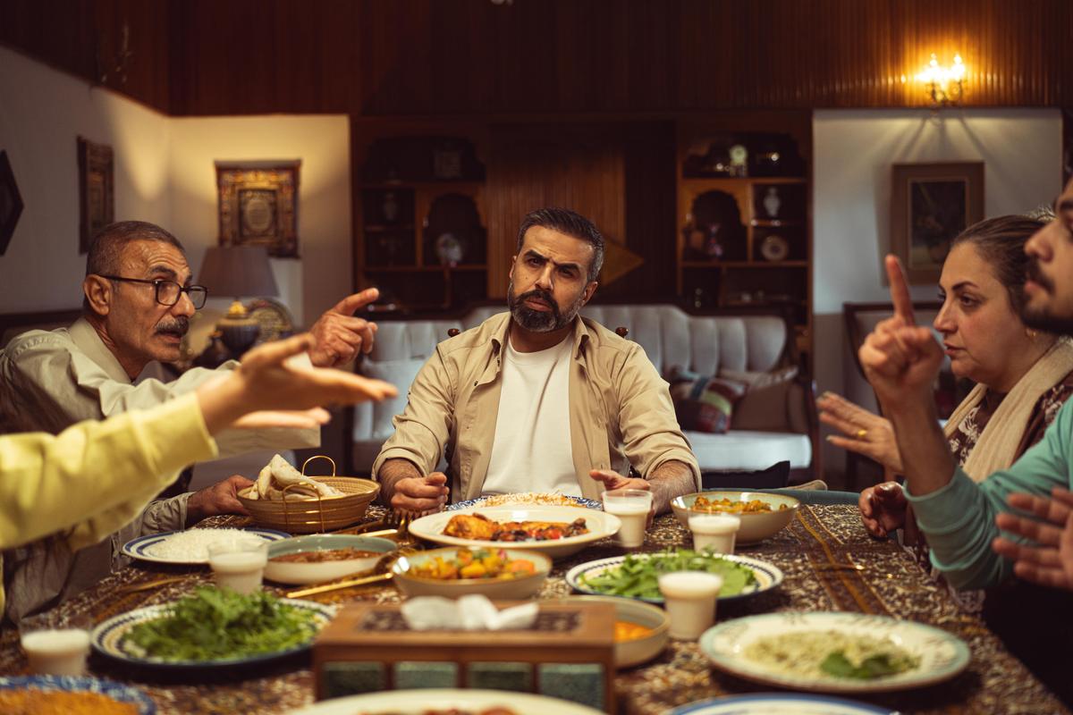 A family seated around a dinner table in a dining room, talking over a shared meal