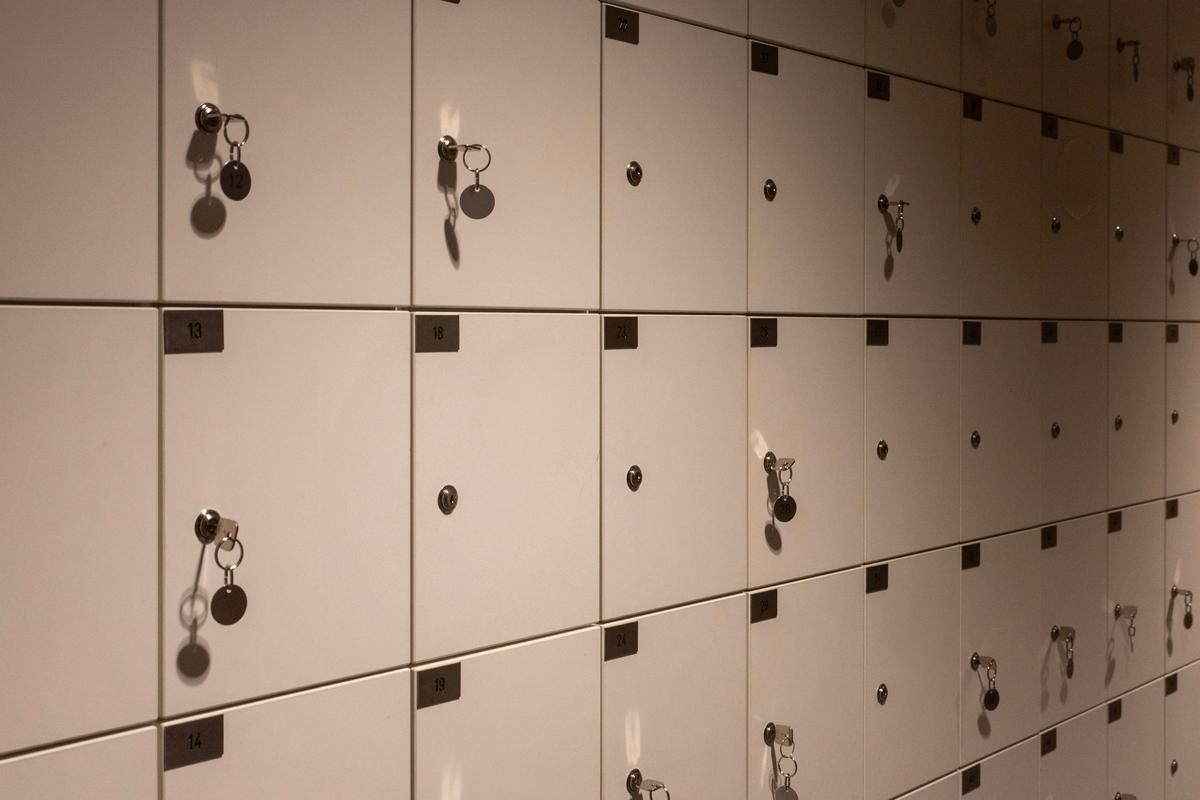 Rows of small wooden lockers with keys in the doors, in soft low light