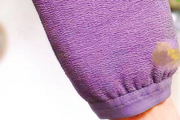 A purple Korean exfoliating mitt worn on a hand