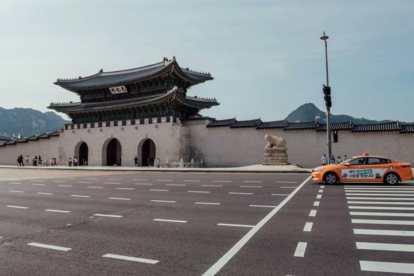 An orange Seoul taxi crossing the road in front of Gwanghwamun Gate