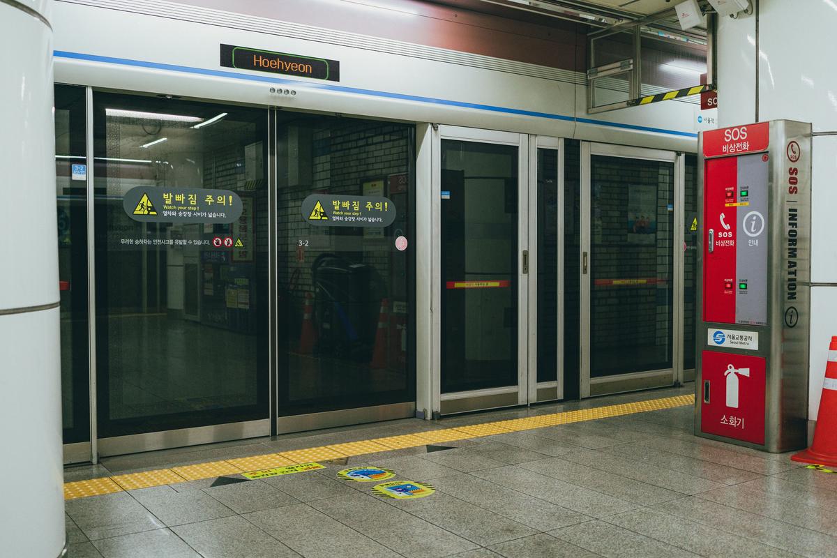 Platform screen doors at a Seoul subway station, with a red emergency equipment cabinet beside them