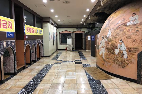 Hallway of a jjimjilbang in Wonju, with a painted dome-shaped kiln sauna, arched rest nooks and a sign for the sleeping room