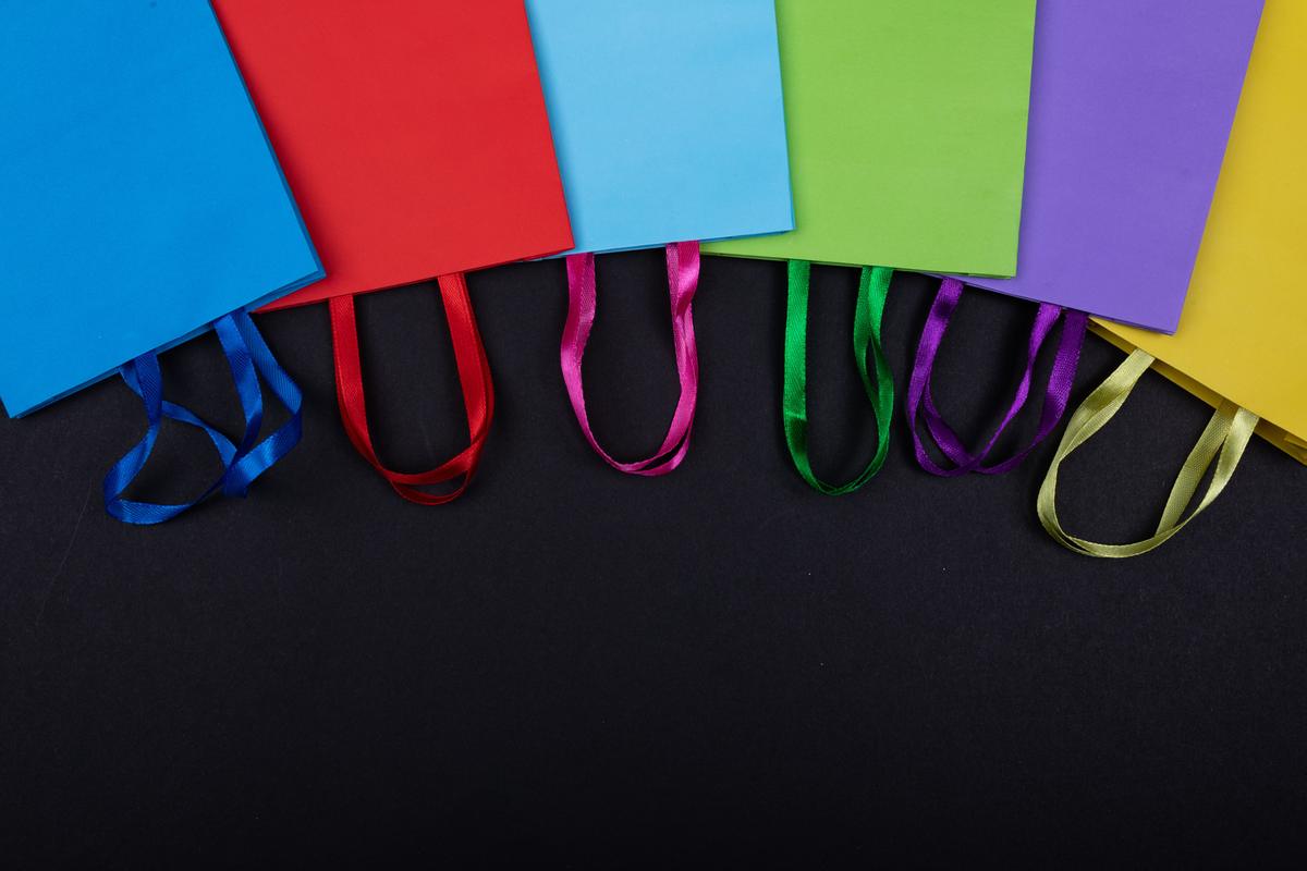 A row of colorful paper shopping bags on a black background